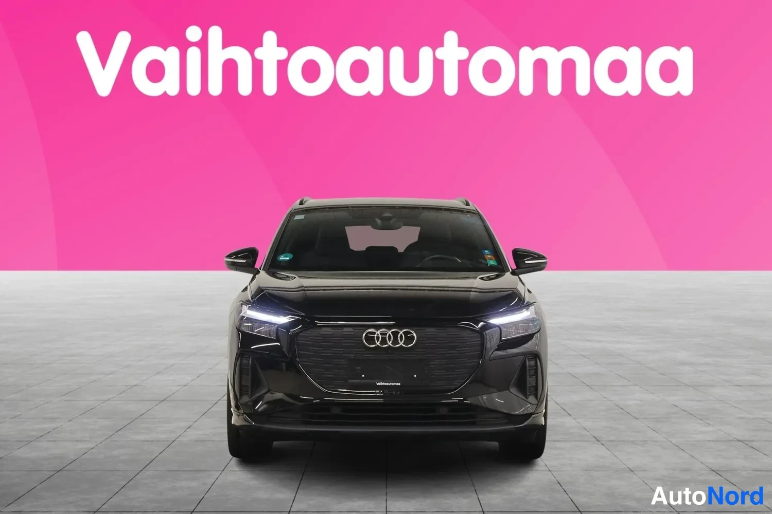 Edestä: Musta Audi Q4 e-tron suoraan edestä valot päällä