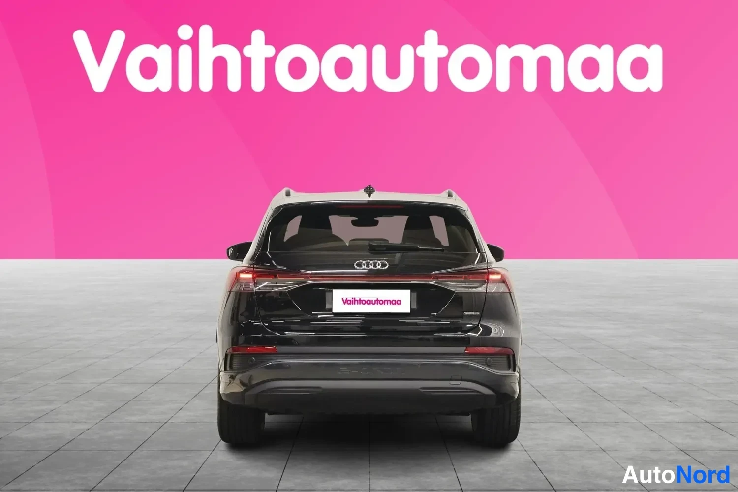 Takaa: Mustan Audi Q4 e-tronin suora takakuva, takavalot ja takaosa studiotaustassa.