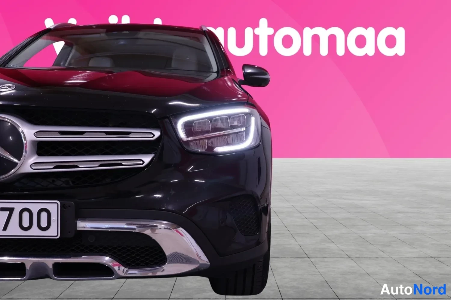Edestä: Lähikuva mustan Mercedes-Benzin etuosasta, etugrilli ja ajovalot näkyvissä.