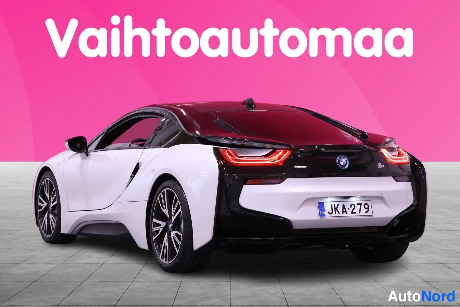 Takaviisto: BMW i8 takaviisto oikealta: Valkoinen kori, punainen katto-osa ja musta perä, U-muotoiset takavalot ja rekisteritunnus.