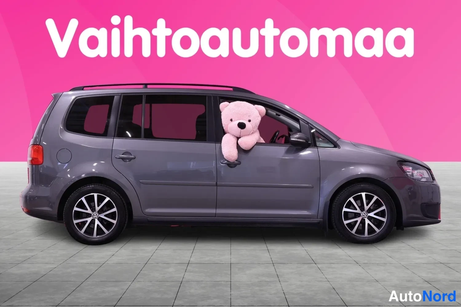 Etuviisto, nokka oikealle: Harmaa tila-auto sivulta etukulmasta, etunenä oikealla, katto-kaiteet ja kevytmetallivanteet.