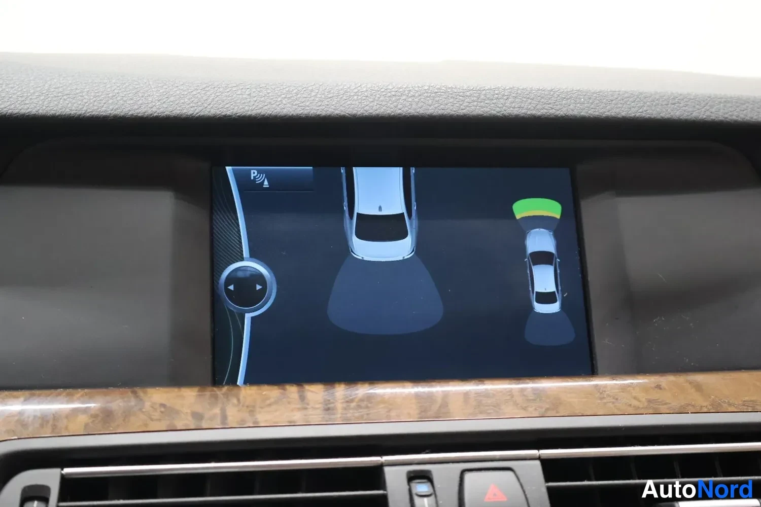 Muu: Kojelaudan näyttö näyttää pysäköintitutkan kuvan, jossa auto ja tunnistettu este ovat grafiikkana. Reservinappi ja ilmastointilaitteet näkyvät alareunassa.