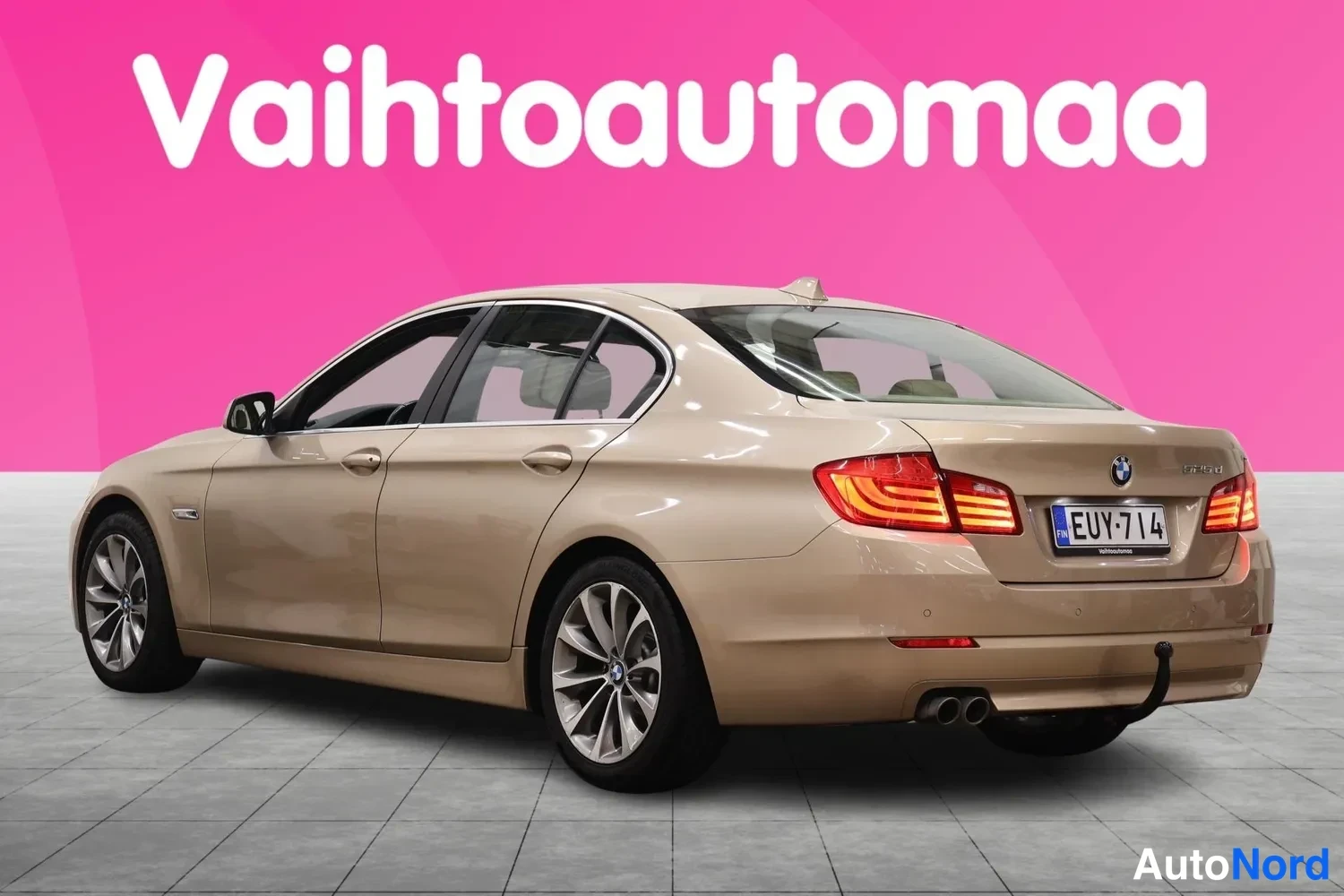 Takaviisto: Beige sedan takaa sivusta, rekisteritunnus, kahden pakoputken jenkit näkyvät.