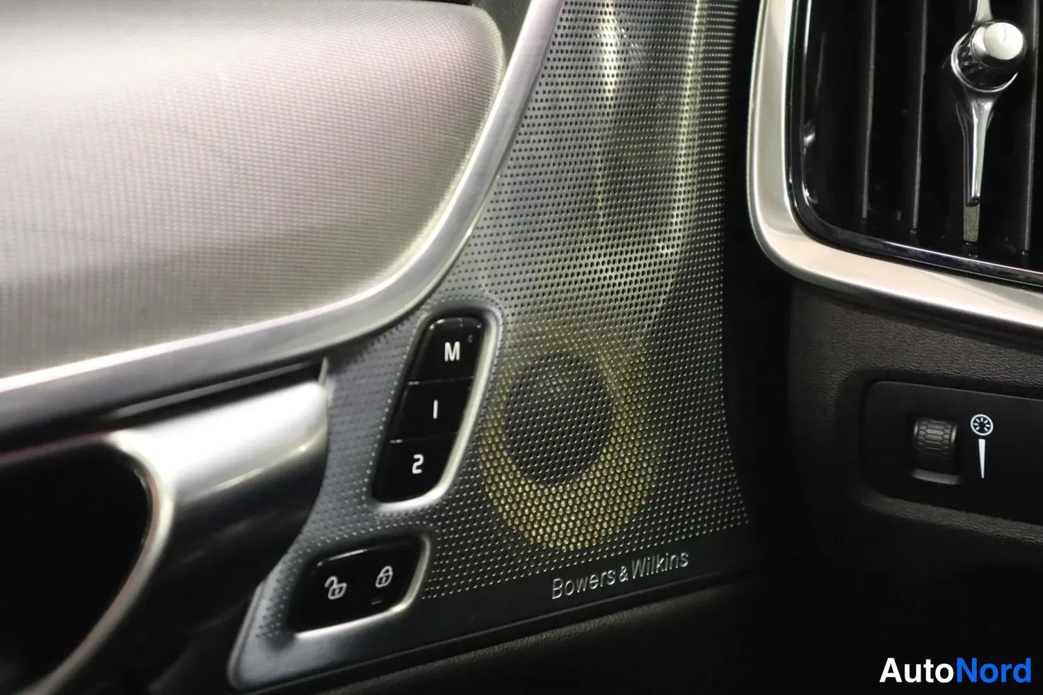Yksityiskohta: Ovensisäpaneelin osa, jossa muistipenkkien säätönäppäimet M, 1 ja 2, lukitus- ja avausnapit, sekä takaa Bowers & Wilkins -merkitty kaiutinverkko.