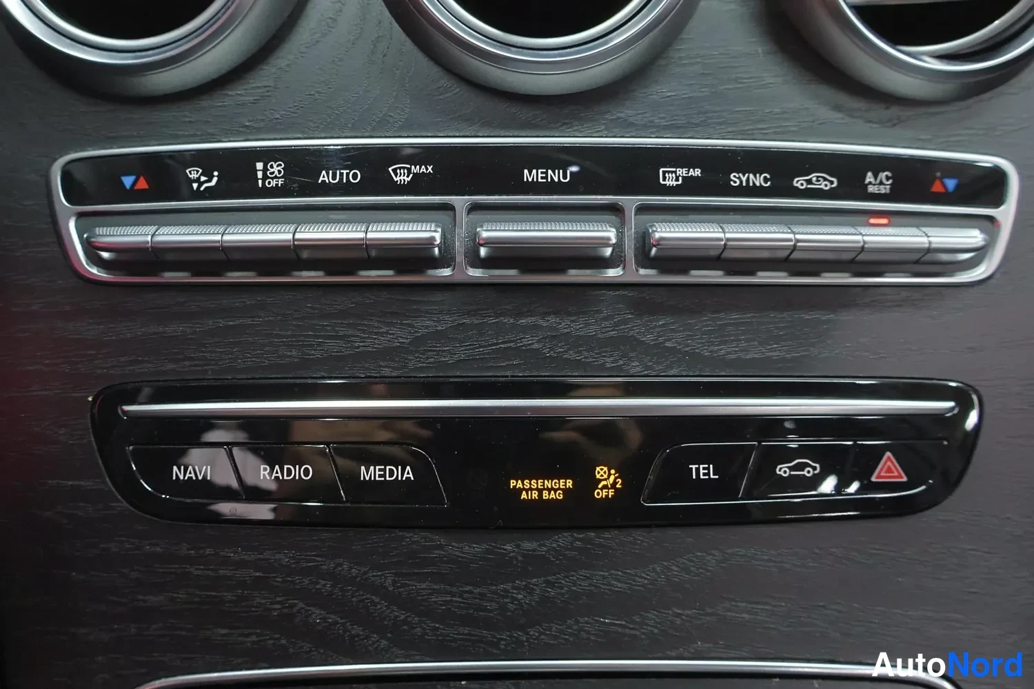 Muu: Keskikonsolin ilmastointi- ja mediapainikkeet lähikuvassa, merkinnöinä muun muassa AUTO, MENU, SYNC, A/C, NAVI, RADIO, MEDIA, TEL.