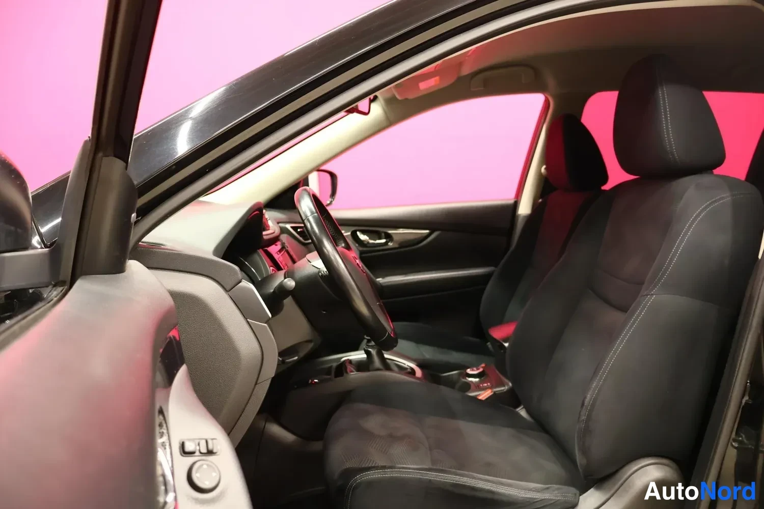 Yksityiskohta: Nissan X-Trailin etuistuimet ja ohjaamotila mustalla kankaallisella verhoilulla, kuvattu kuljettajan oven kautta.