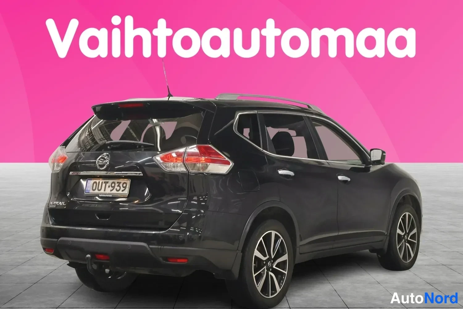 Takaviisto: Musta Nissan X-Trail takaa- ja sivusuunnasta kuvattuna, rekisterikilpi, laatikkotyyliset kattokaiteet ja perävaunukytkin näkyvät.