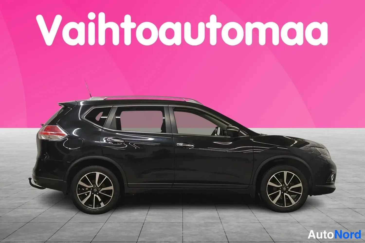 Sivulta: Mustan Nissan X-Trailin sivuprofiili vasemmalta kuvattuna studio-tyylisellä pinkillä taustalla.