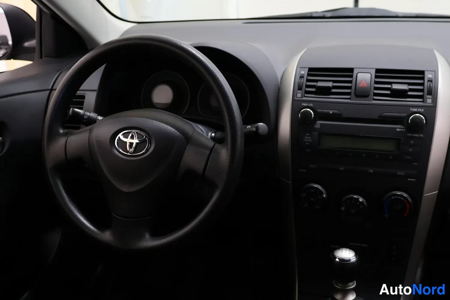 Yksityiskohta: Ohjaamo vasemmalta: Toyota-ohjauspyörä, kojelauta ja keskikonsolin radio sekä manuaalivaihteen vipu.