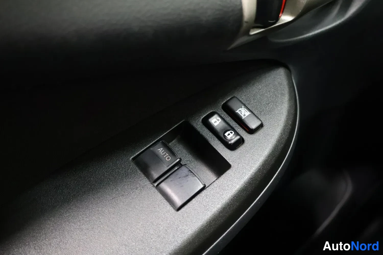 Yksityiskohta: Autoverhon säädin (AUTO) ja ovilukkojen painikkeet kuljettajan oven sisäpaneelissa.