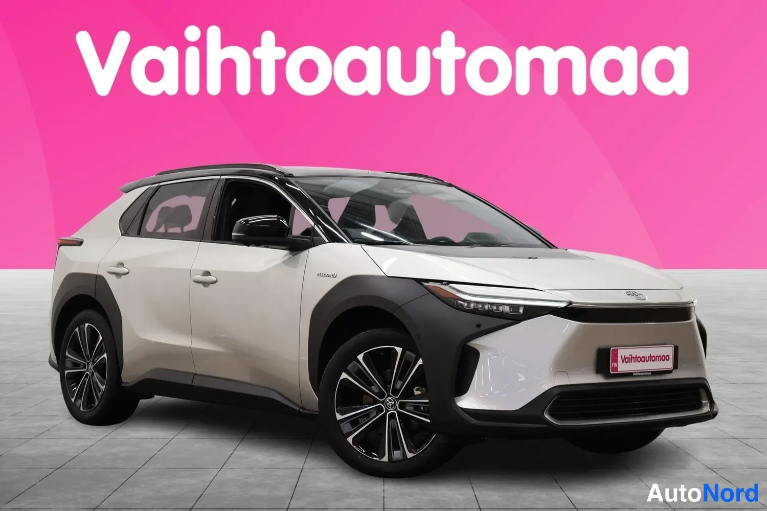 Etuviisto, nokka oikealle: Valkoinen Toyota bZ4X kulmasta edestä oikealta kuvattuna, musta katto ja alempi suojaus.