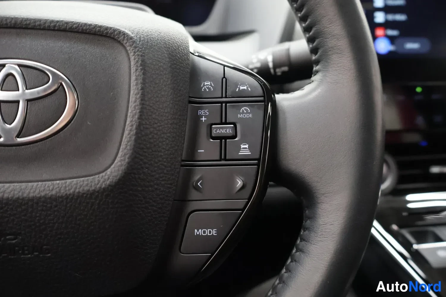 Yksityiskohta: Ohjauspyörän oikea puhelin ja rattoirinäppäimet Toyota-logolla; näkyvät RES+, MODE, CANCEL ja ALC-nuolet.