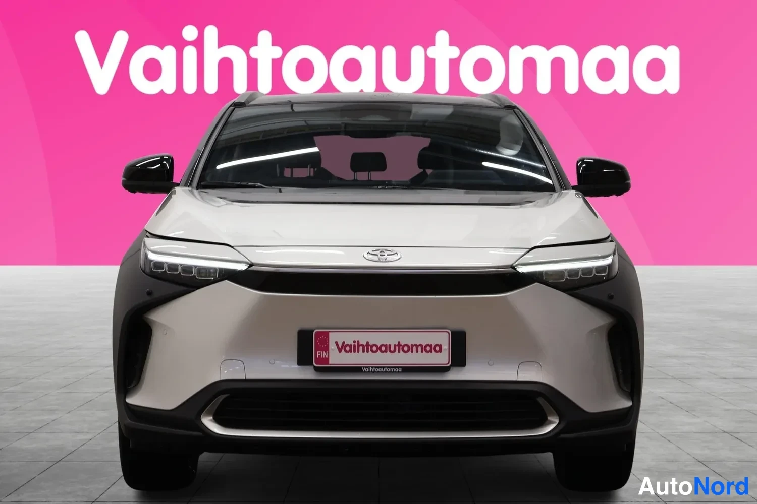 Edestä: Valkoinen Toyota bZ4X suoraan edestä, kylkituulet ja etukatteinen etusumu.