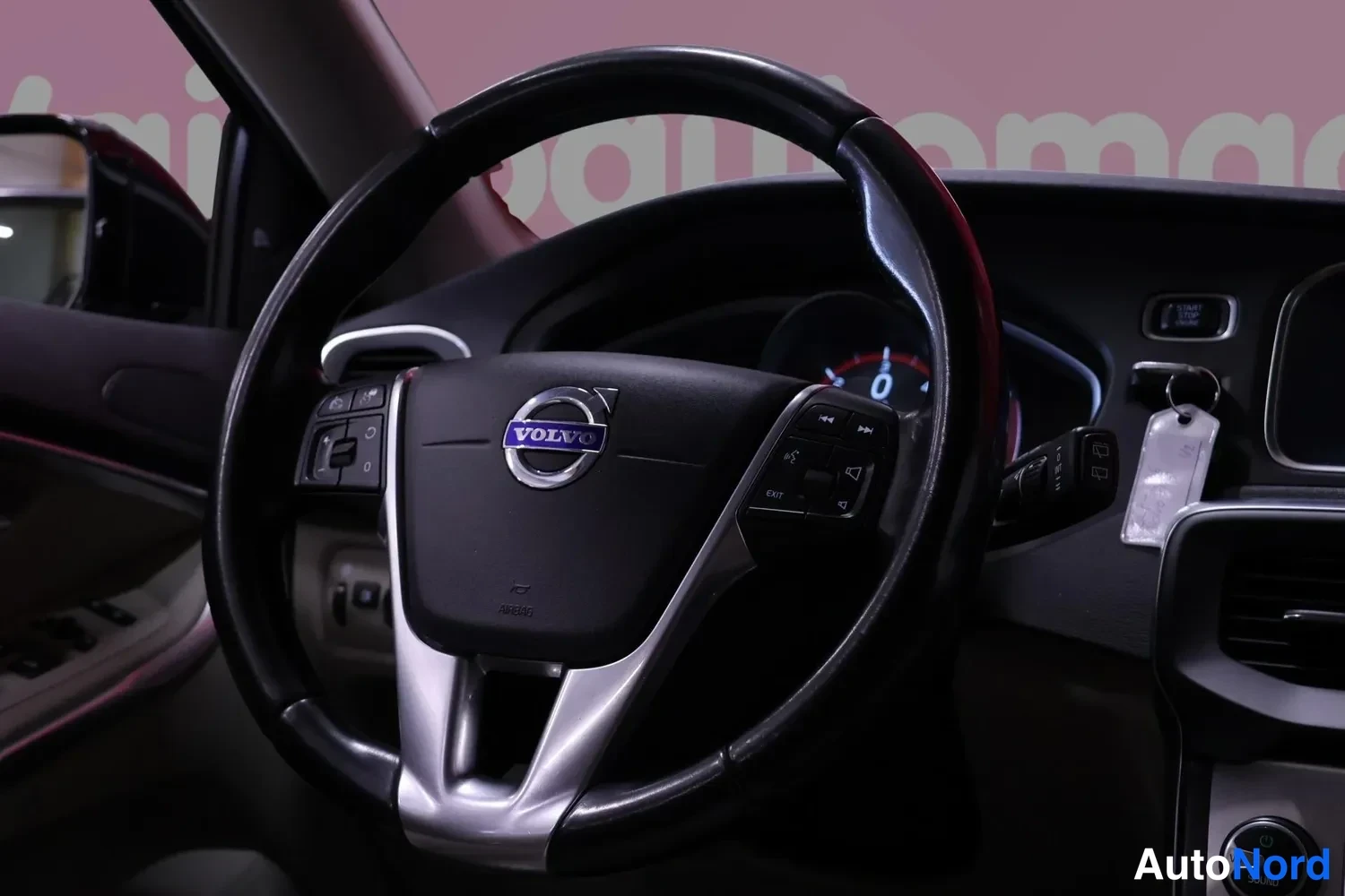 Muu: Volvo-merkillä varustettu ohjauspyörä lähikuvassa, taustalla mittaristo ja avain virtalukossa.