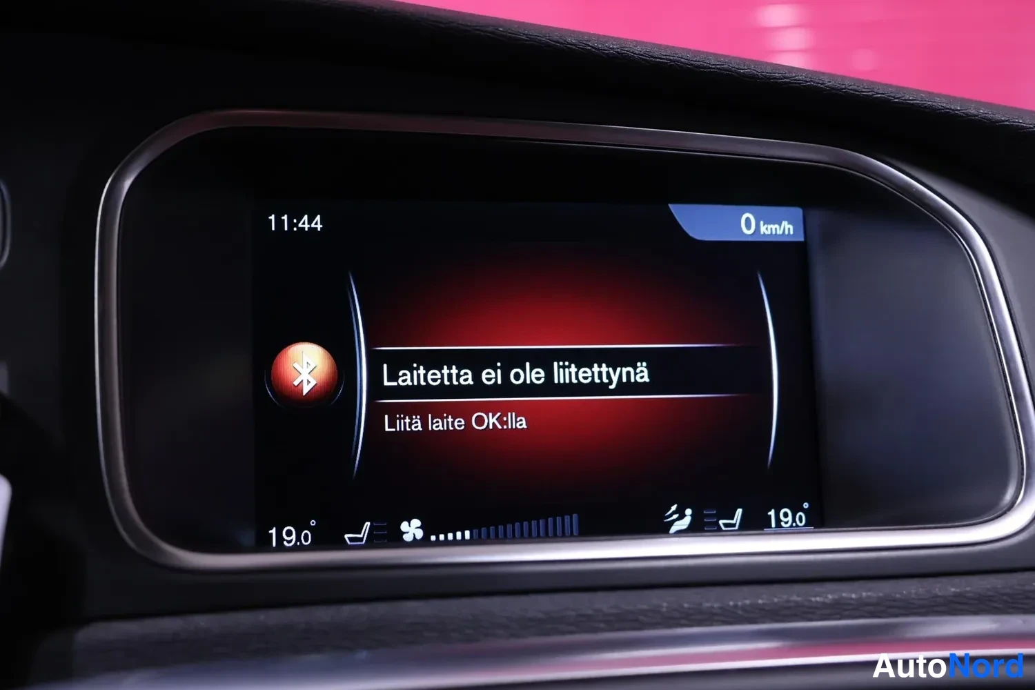 Muu: Keskiösumun infotainment-näyttö ilmoittaa punaisella taustalla 'Laitetta ei ole liitetynä' ja ohje 'Liitä laite OK:lla', kello 11:44 ja nopeus 0 km/h.