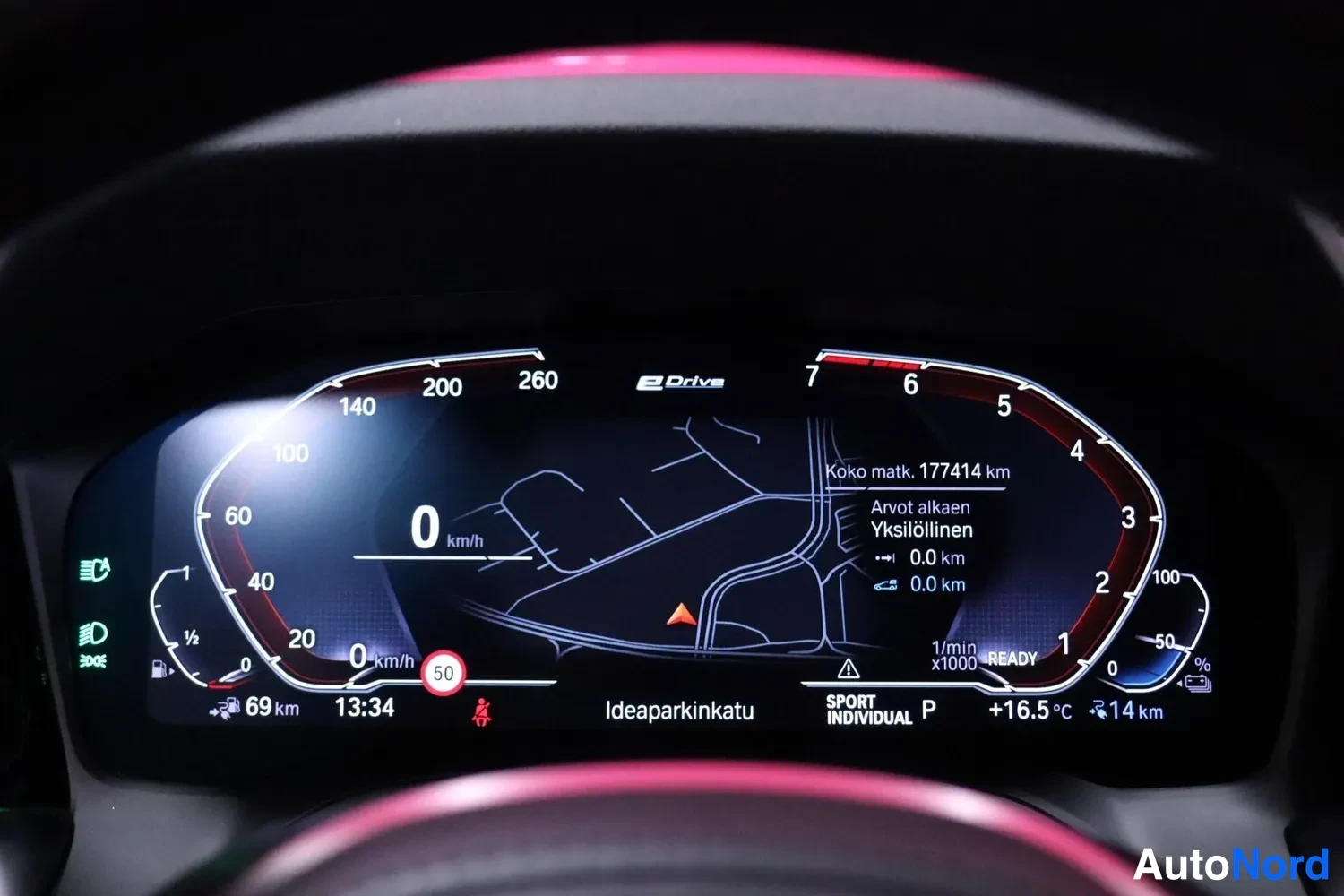 Yksityiskohta: BMW:n digitaalinen mittaristo näyttää nopeuden 0 km/h, kokonaismatkan 177414 km, kellon 13:34, ulkolämpötilan +16.5 °C, ajotilan SPORT INDIVIDUAL ja eDrive-merk