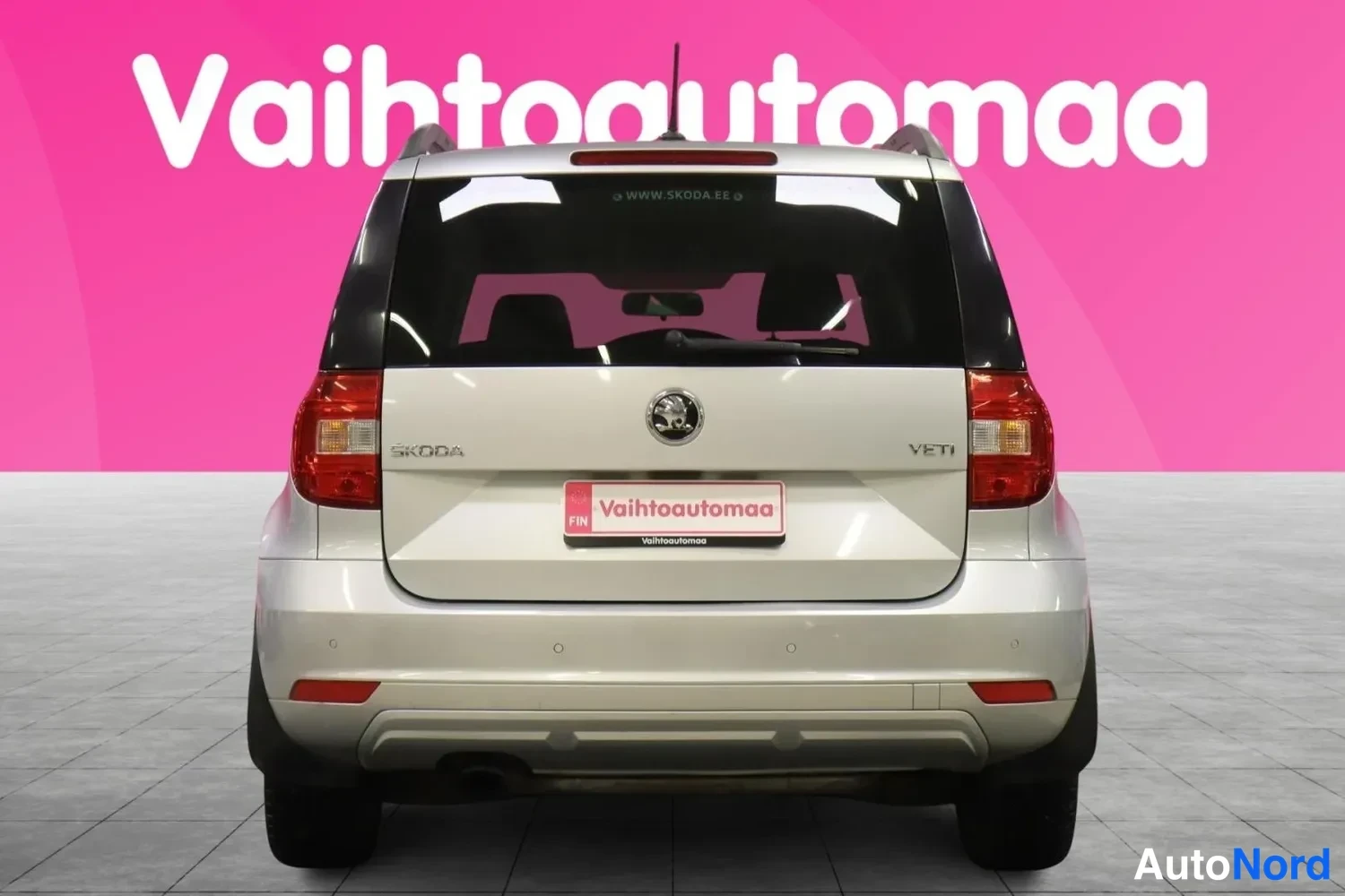 Takaa: Hopeanvärinen tila-auto suoraan takaa, punaiset takavalot, Skoda-merkki ja YETI-teksti tavaratilan kannella, takalasinraapija näkyvissä.
