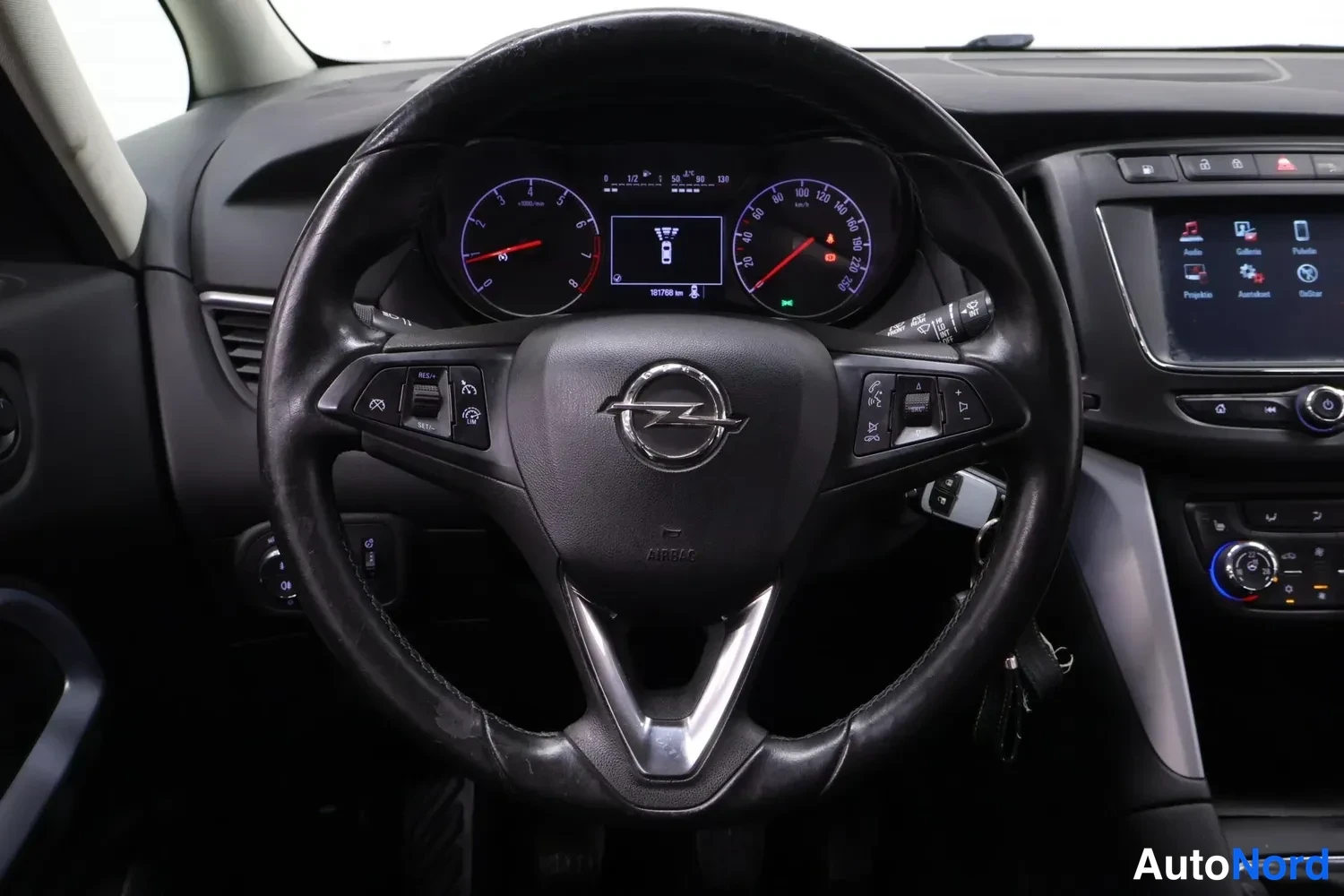 Muu: Lähikuva Opel-ohjauspyörästä ja mittaristosta; matkamittari näyttää 167799 km.