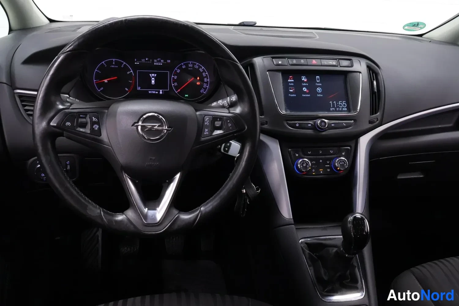 Muu: Kuljettajan puolen näkymä: Opel-ohjauspyörä, mittaristo (167799 km), kosketusnäyttö ja manuaalivaihteen vaihtokeppi, kello 11:55.