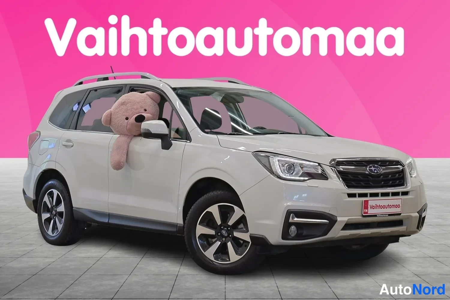 Etuviisto, nokka oikealle: Vaalean SUV-auton etukulmakuva oikealta, etupanssaritinä ja ajovalot näkyvät, taustalla vaaleanpunainen Vahtoautomaa-banner.