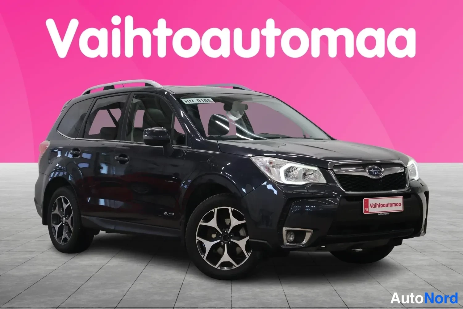 Etuviisto, nokka oikealle: Tummanharmaa Subaru Forester etukulmasta oikealta, katolla kattokaiteet ja pyörät kolmi kannet.