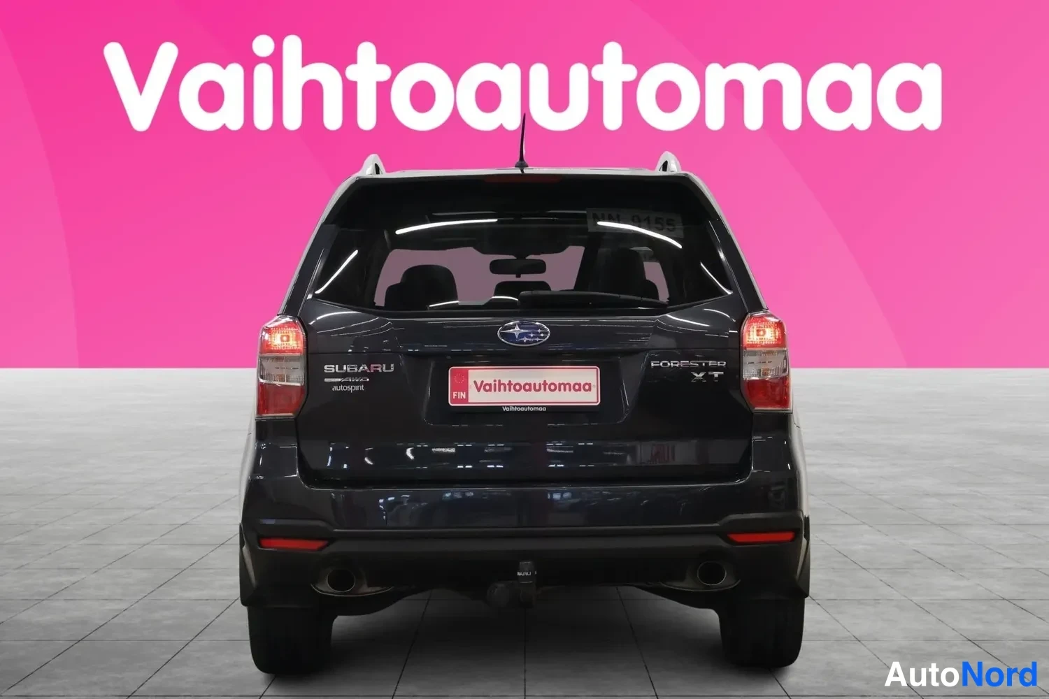 Takaa: Subaru Forester XT:n takaapäin otettu kuva: tummansininen kori, SUBARU- ja FORESTER XT-merkinnät, Vaihtoautomaa-kyltti rekisterin paikalla.