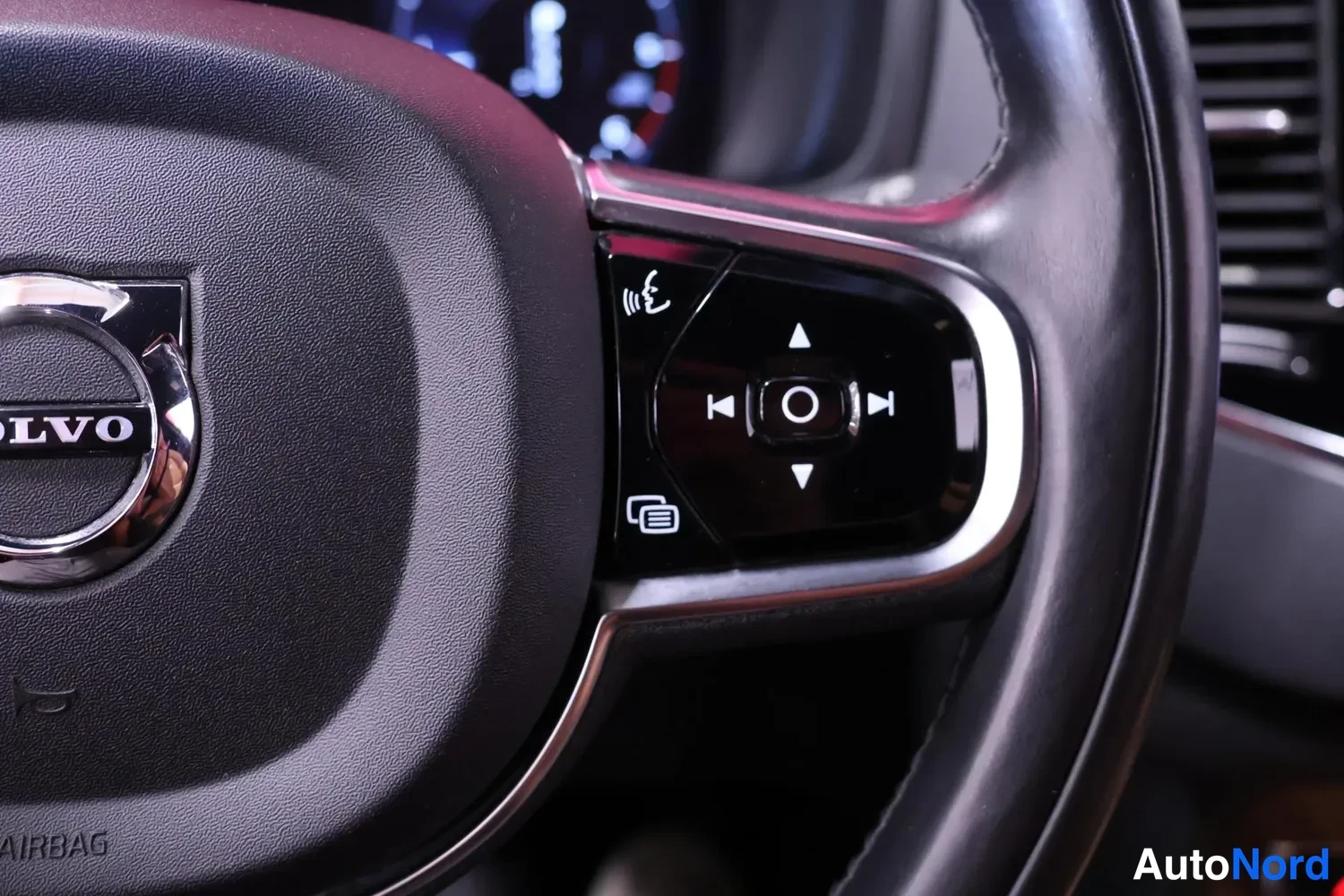 Muu: Volvo-ohjauspyörän vasemman puolen painikkeet lähikuvassa, AIRBAG-teksti näkyvissä.