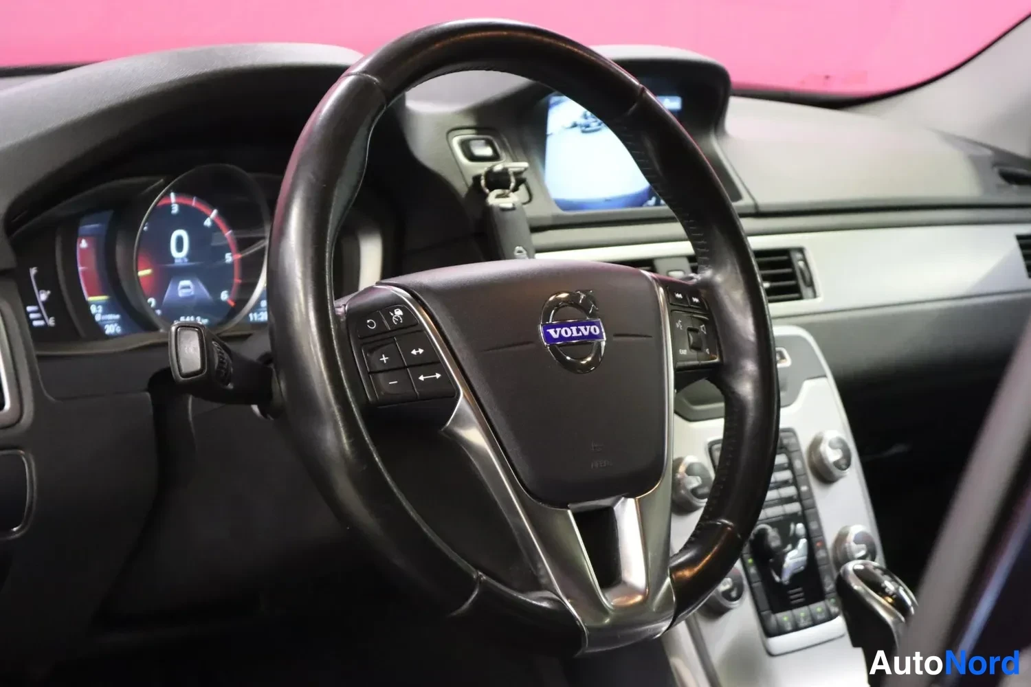 Muu: Volvo-ohjauspyörä ja kojelauta, jossa näkyy infotain-näytöllä peruutuskamerakuva.