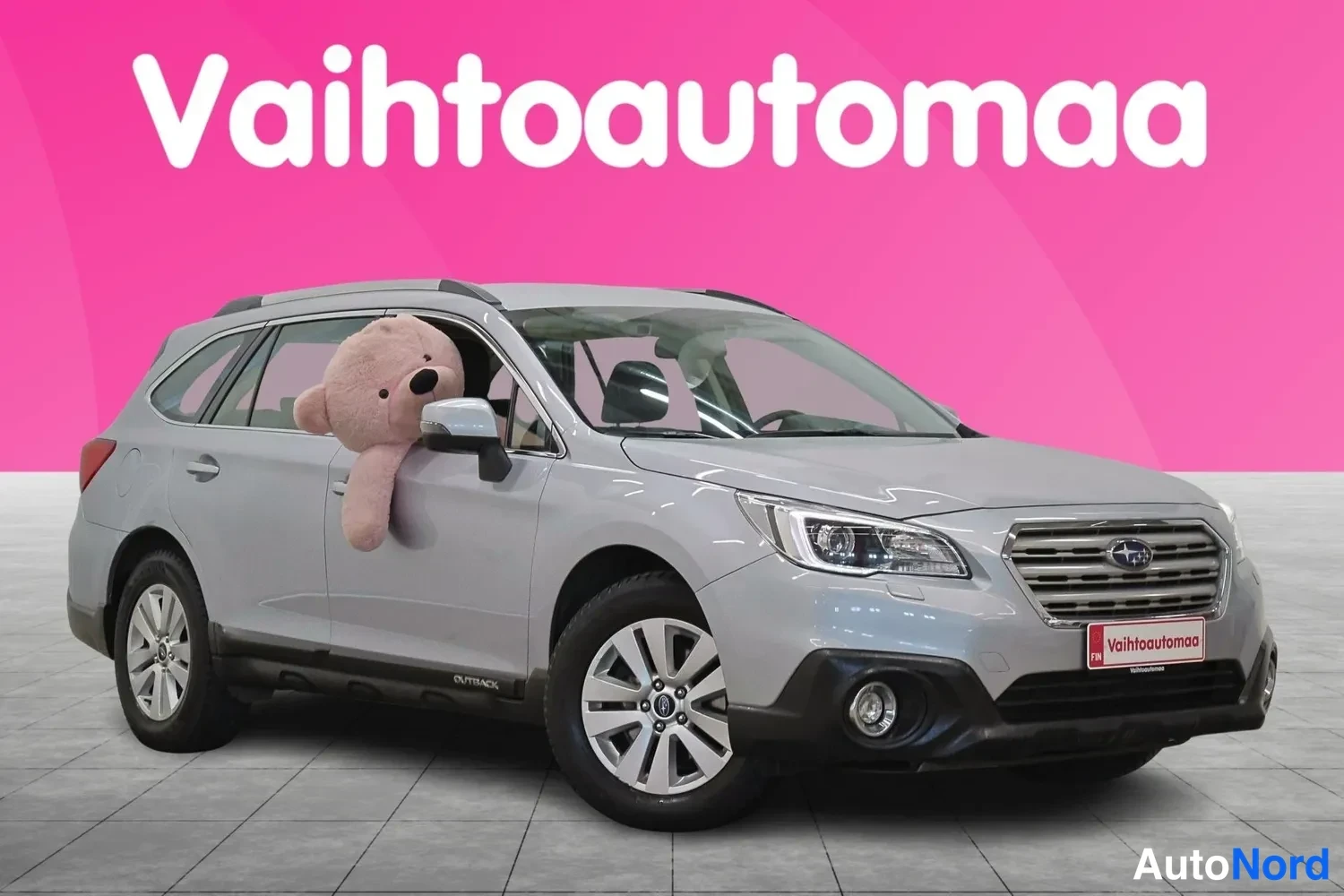 Etuviisto, nokka oikealle: Silver Subaru Outback station wagon in front three-quarter view. The rear wheel is visible on the right side of the image while the grille and front bump