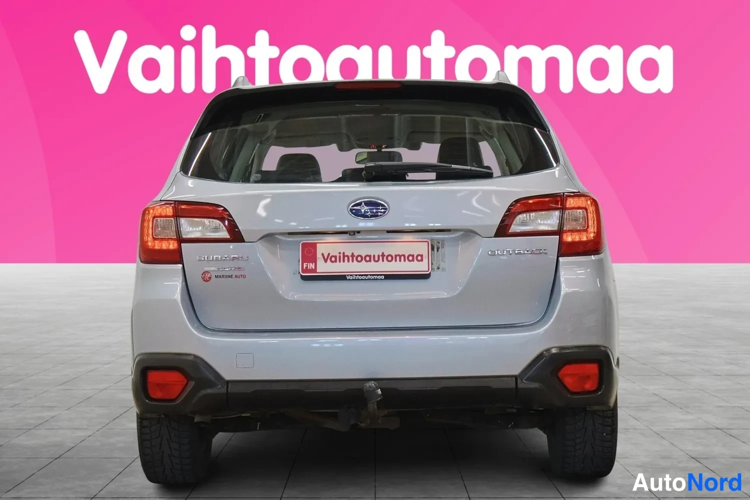Takaa: Auton takaosa suoraan takaa, SUBARU- ja OUTBACK-tekstit tavaratilan kannessa, auton takaan avattu.