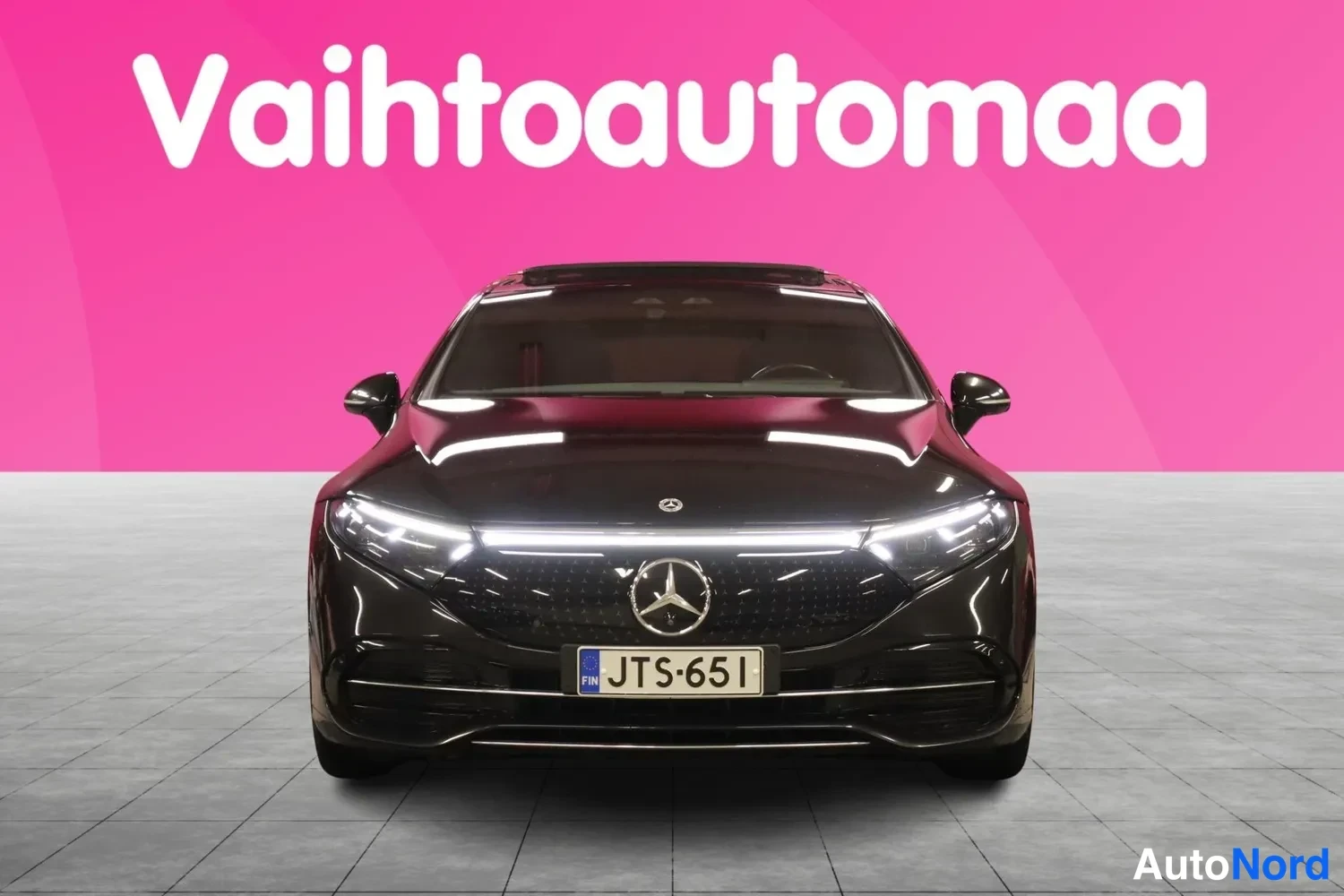 Edestä: Mustan Mercedes-Benz EQS:n edessäpäinkuva, rekisteri, vaalea LED-palkki keulaikkunassa.