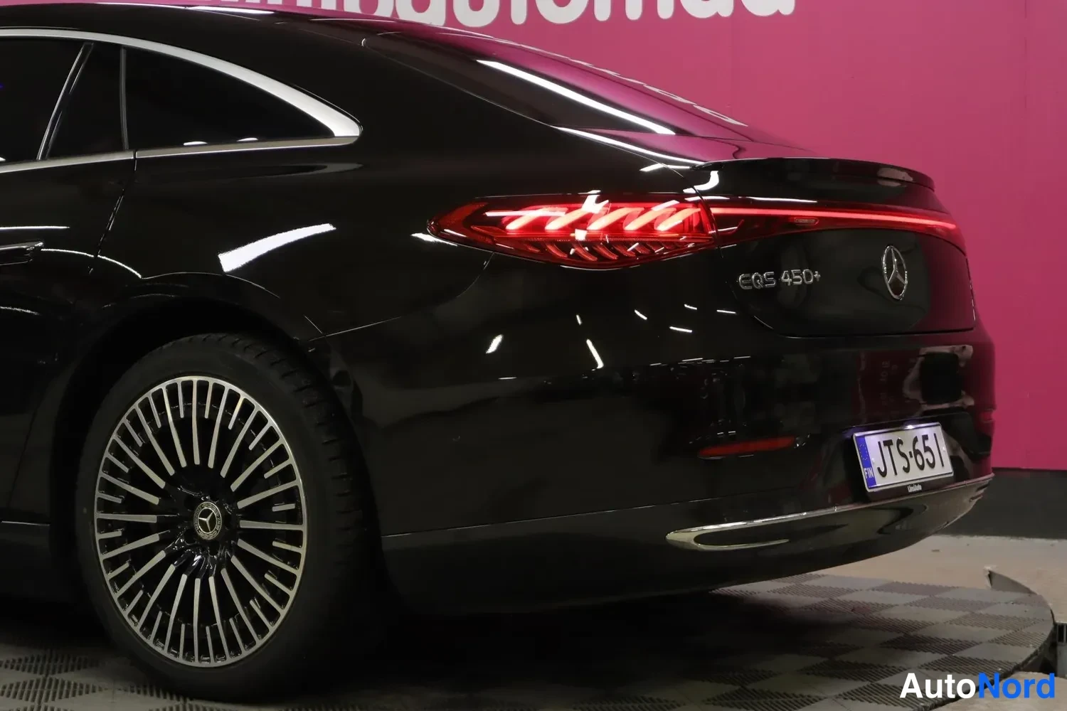 Takaviisto: Mustan Mercedes-Benz EQS:n takakolmannesnäkymä lähikuva LED-takavalosta, EQS 450+ -merkinnästä ja rekisteritunnuksesta.