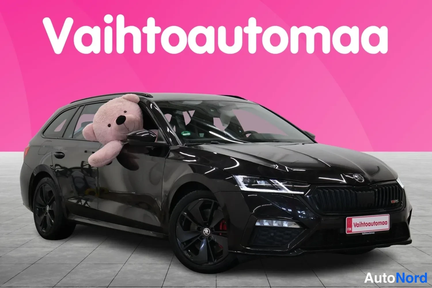 Etuviisto, nokka oikealle: Musta Skoda Octavia Combi seisoo vaalealla laattalattiala, takatutkat ikkunasta. Takaseinä ja oikea sivu näkyvät.