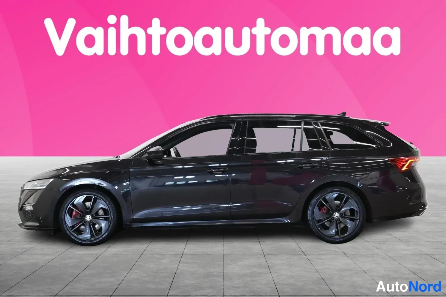 Sivulta: Musta farmarikori auto sivulta kuvattuna, tummat vanteet ja katolla tutkamainen antenni.