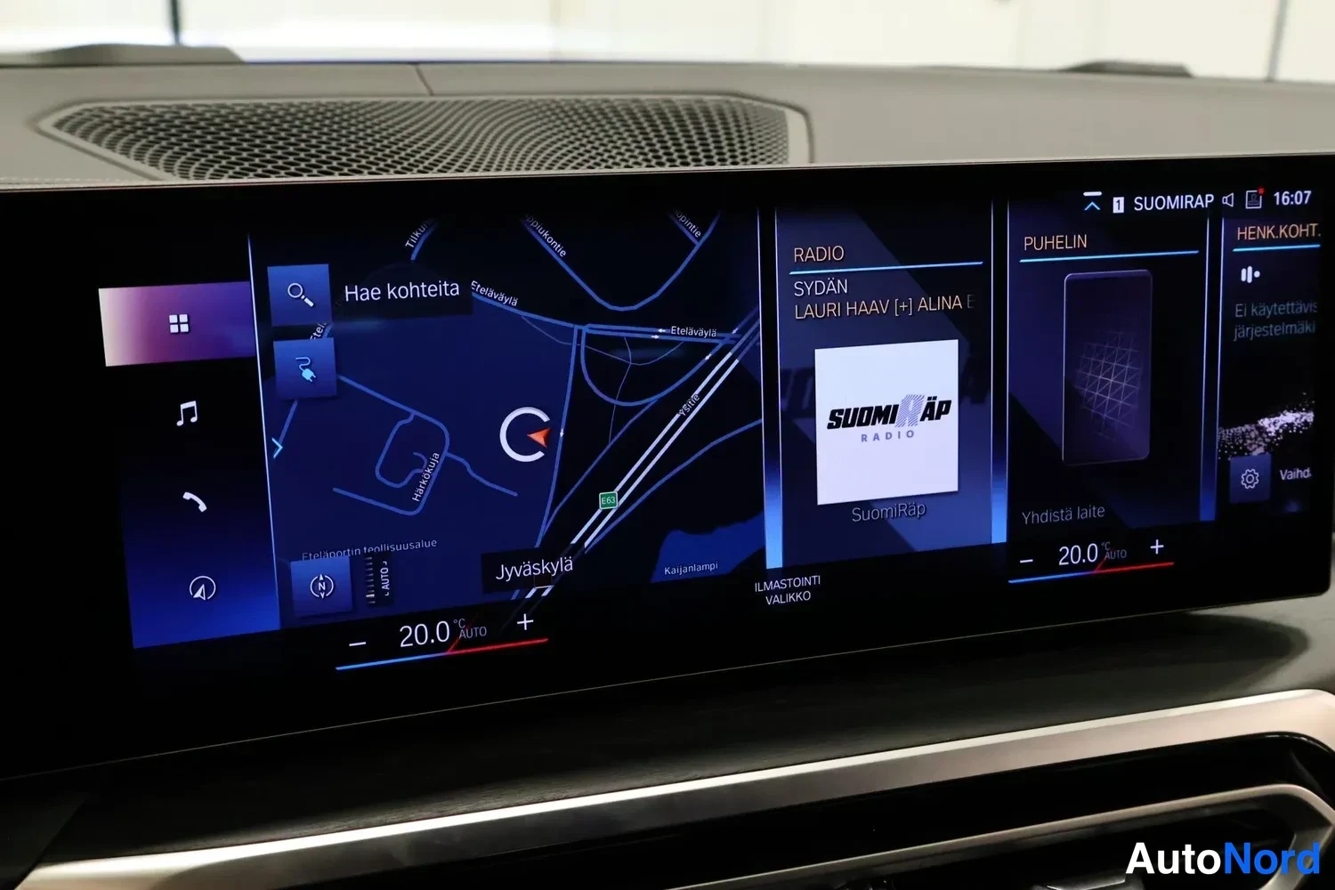 Muu: Auton infotainment-näyttö lähikuvassa: karttanavigaatio paikkakunnalla Jyväskylä, radio SuomiRap, puhelimen yhdistämisvalikko ja ilmastoinnin 20,0 asteen automa