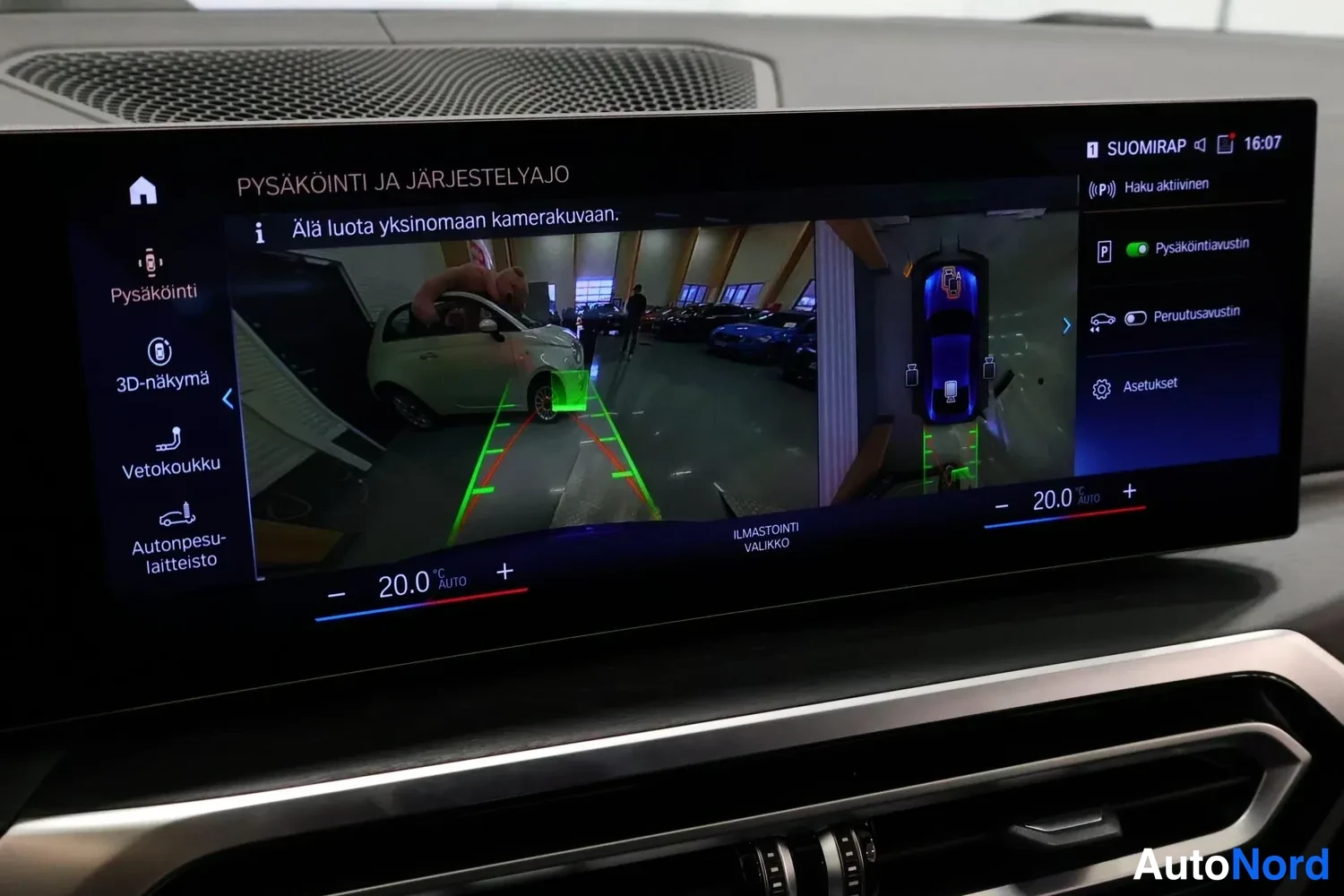 Sivulta: Auton kojelaudan infotainment-näyttö näyttää pysäköintikameran kuvan ja 3D-näkymän, valikossa pysäköintitoiminnot.