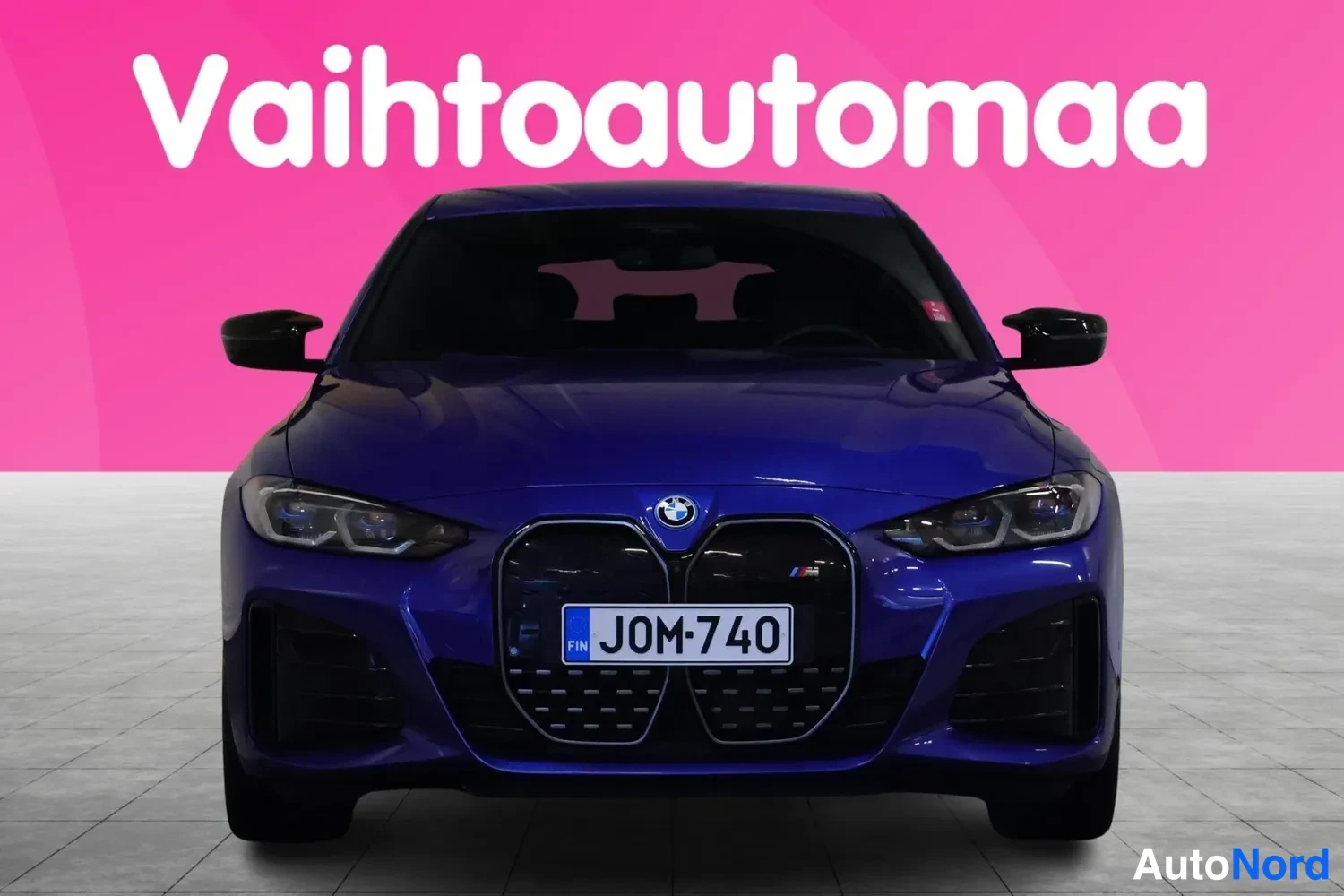 Edestä: Sininen BMW suoraan edestä näkyvällä keulalla, suurella grillellä ja rekisterikilvellä.