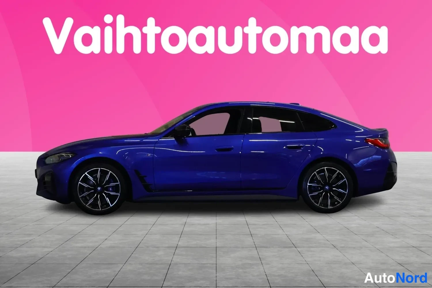 Sivulta: Sininen BMW sivulta nähtynä; vasen kylki, pyörät ja ovet hallinnan lavastuksessa.