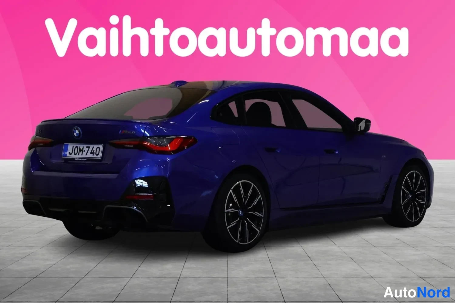 Takaviisto: Taka- ja sivunäkymä sinisestä BMW i4:stä rekisteritunnuksella, mustat kevytmetallivanteet.