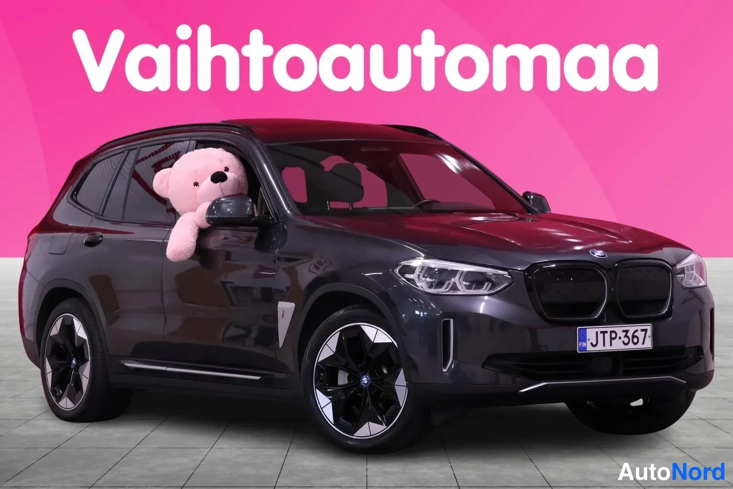Etuviisto, nokka oikealle: Kolmasosikuva tummanharmaasta automallista, jossa on piilotetut etusisävalot ja suuri kehyksellä varustettu etuosa. Pieniä kuvakuvitteita on etuosassa ol