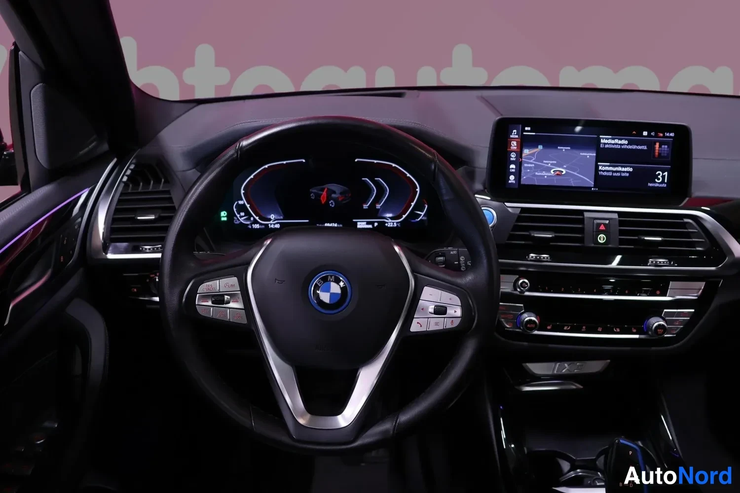 Yksityiskohta: Ohjaamo edestäpäin: BMW-ratti, digitaalinen mittaristo, karttanäkymä näytöllä ja keskikonsolin säätimet.