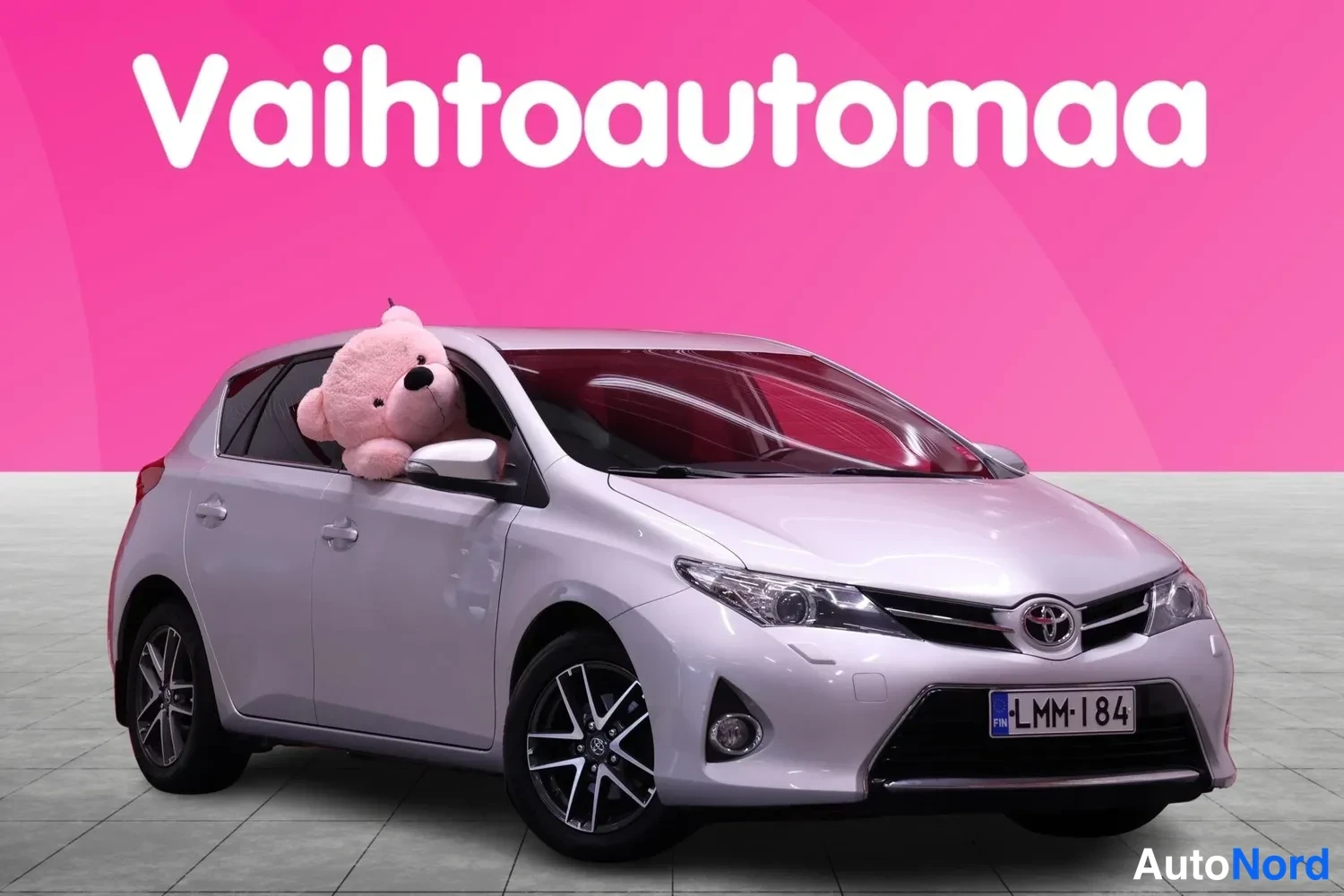 Etuviisto, nokka oikealle: Ennen kolmestoista näkökulma: Hopeanharmaa hatchback, jossa on etusisäkatto, etuvalot ja alumiinivanteet. Lämminpehmeä pehmolelu istuu kuljettajan ikkuna