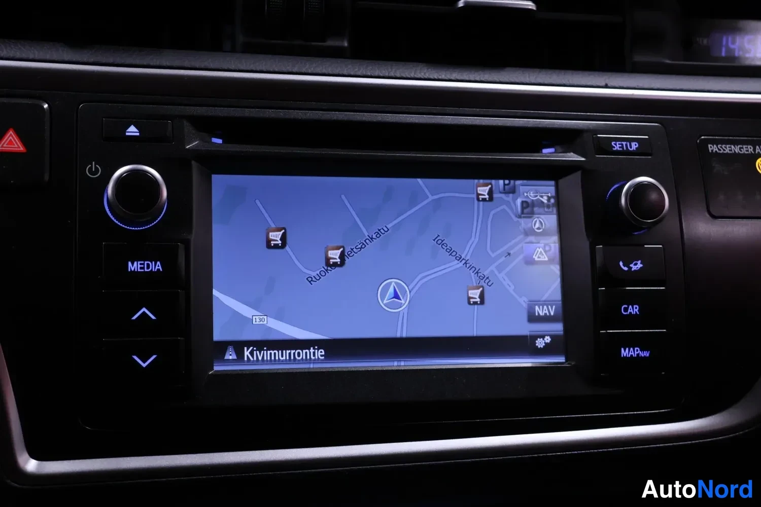 Yksityiskohta: Kojelaudan infotainment-näyttö näyttää karttaaavigointia, napit MEDIA, SETUP, NAV, CAR ja MAP.