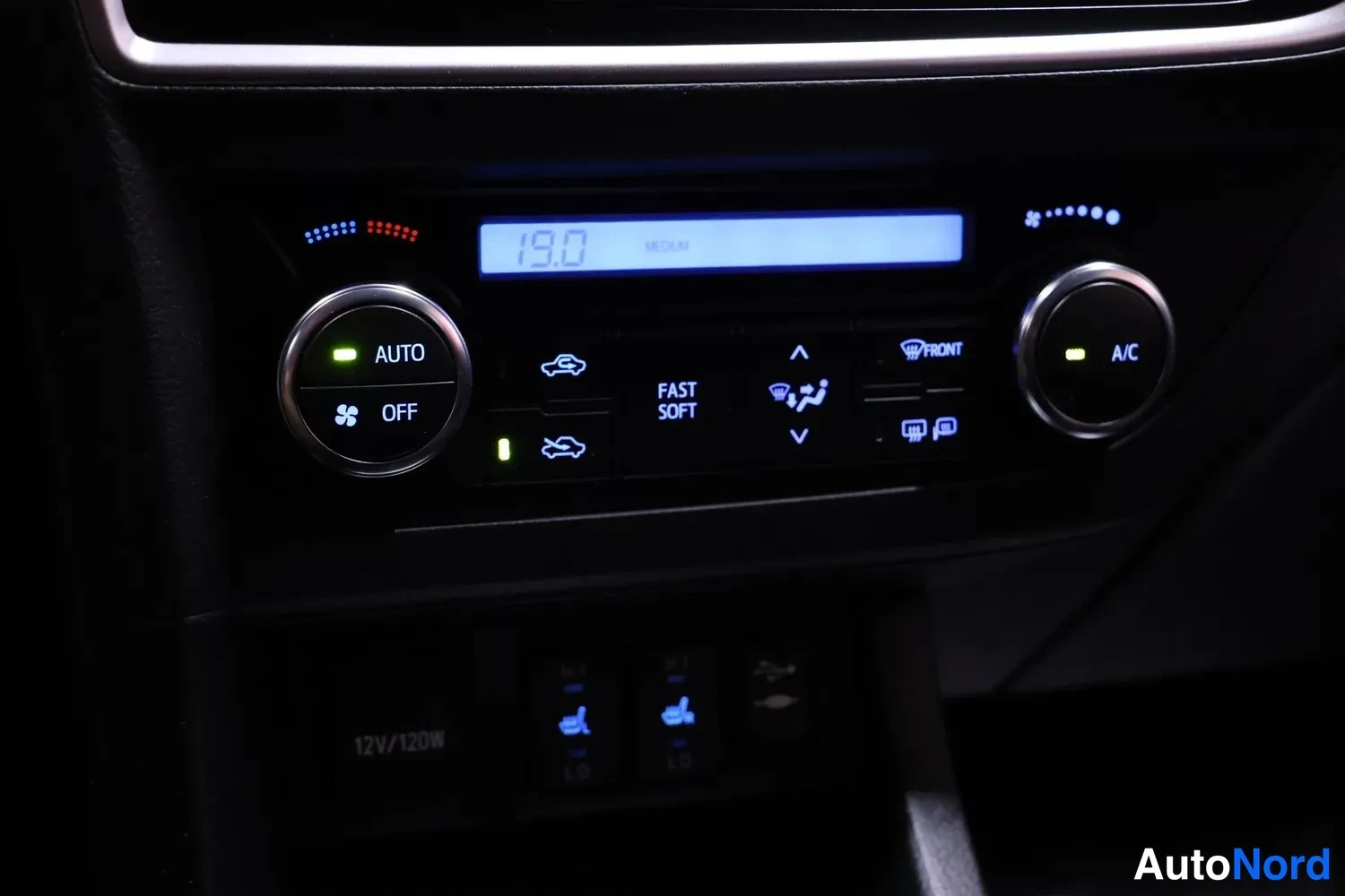 Yksityiskohta: Autojen automaattiset ilmastointilaitteet, jossa näkyvät AUTO- ja OFF-merkinnät, lämpötilanäyttö 19.0 sekä A/C-painike.
