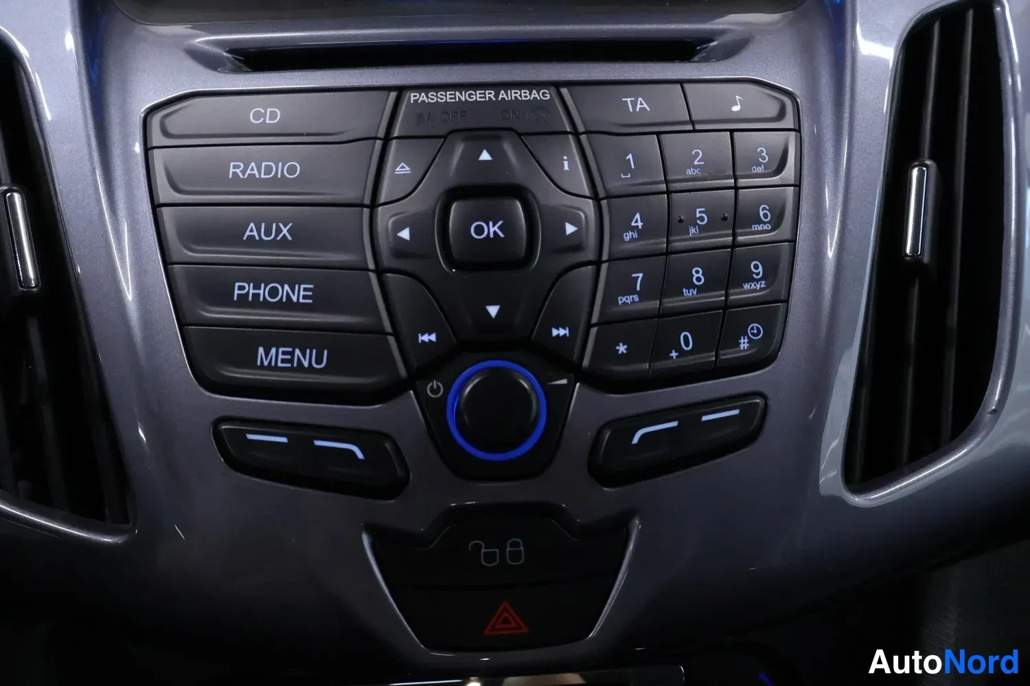 Muu: Autoon keskikäyttöpaneeli, jossa painikkeet CD, RADIO, AUX, PHONE ja MENU sekä numeronäppäimistö ja OK-säätimenappi.