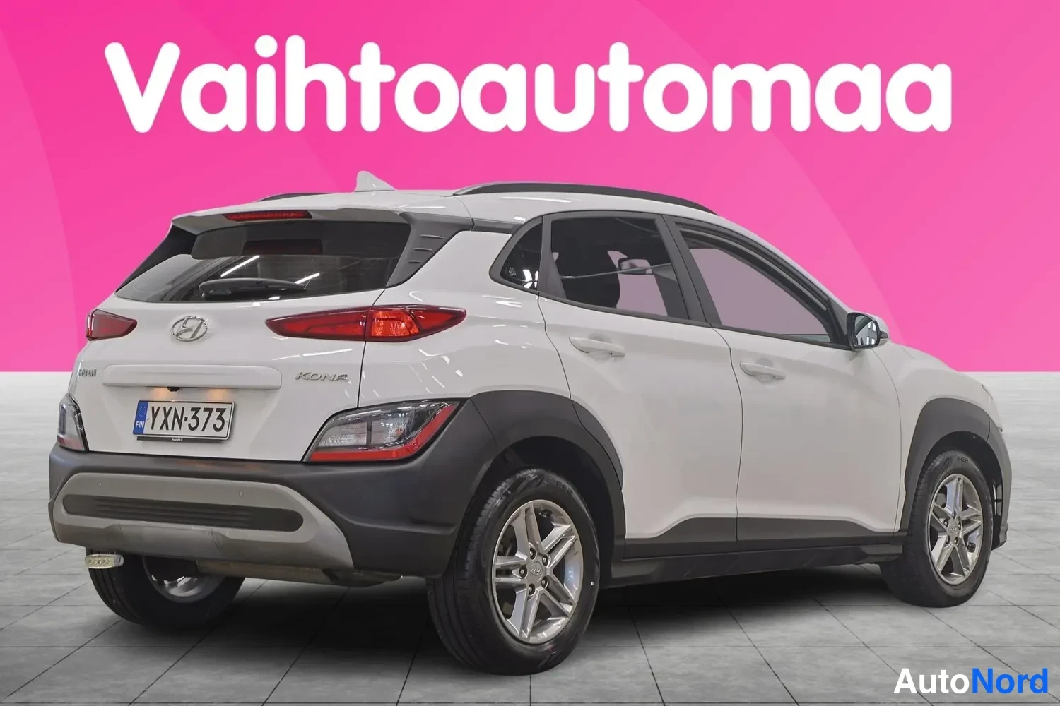 Takaviisto: Valkoisen Hyundai Kona -henkilöauton takakulma oikealta, rekisterikilpi näkyvissä.