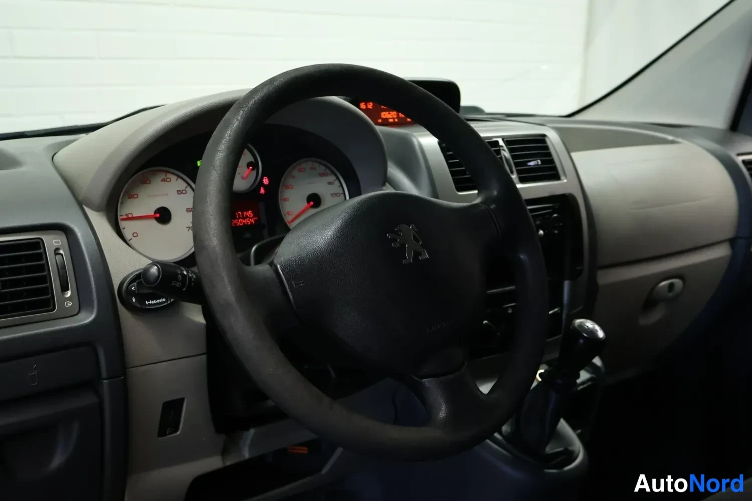 Sivulta: Kojetaulu ja ohjauspyörä: mittarit ja lukumatka näkyvät, Peugeot'n merkki ohjauspyörässä.