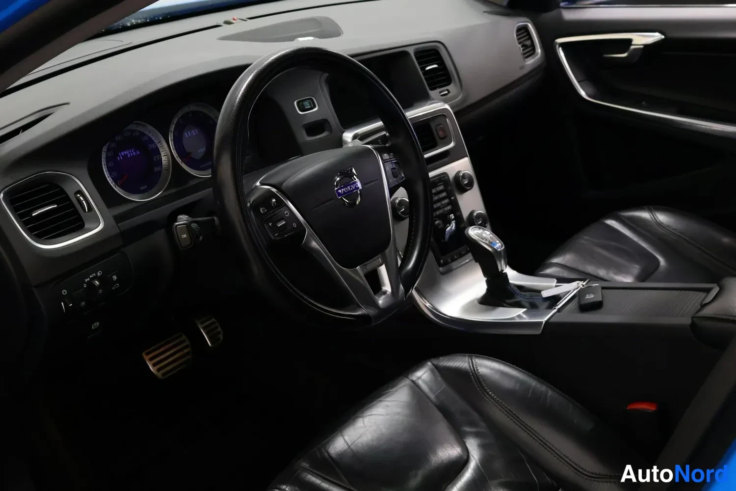 Muu: Auton sisätilat: Volvo-ohjauspyörä, mittaristo, keskikonsoli ja vaihdin, mustat nahkaistuimet.