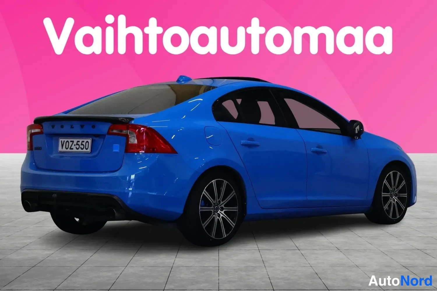 Takaviisto: Sininen sedan takaa ja vasemmalta sivulta kuvattuna; takaluukussa VOLVO-teksti, rekisterikilpi V0Z-550, punaiset takavalot ja kaksoispakoputki näkyvät.