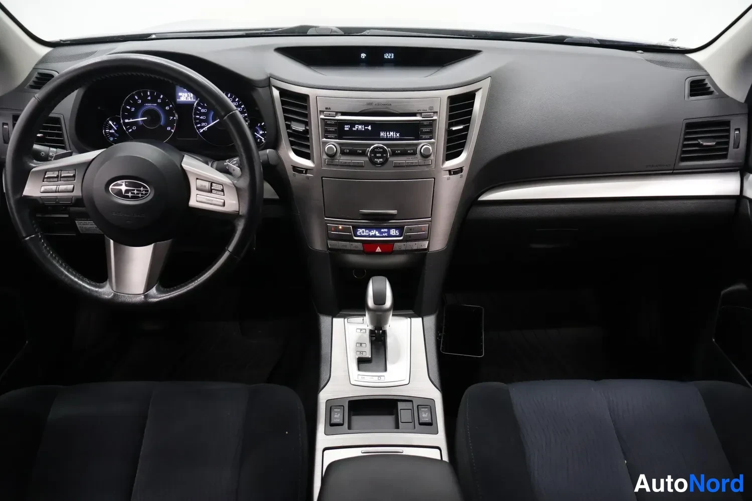 Muu: Ohjaamo ylhäältä: Subaru-ohjauspyörä, mittaristo, keskikonsolin automaattivaihteen valitsin ja radio, mustat penkit.